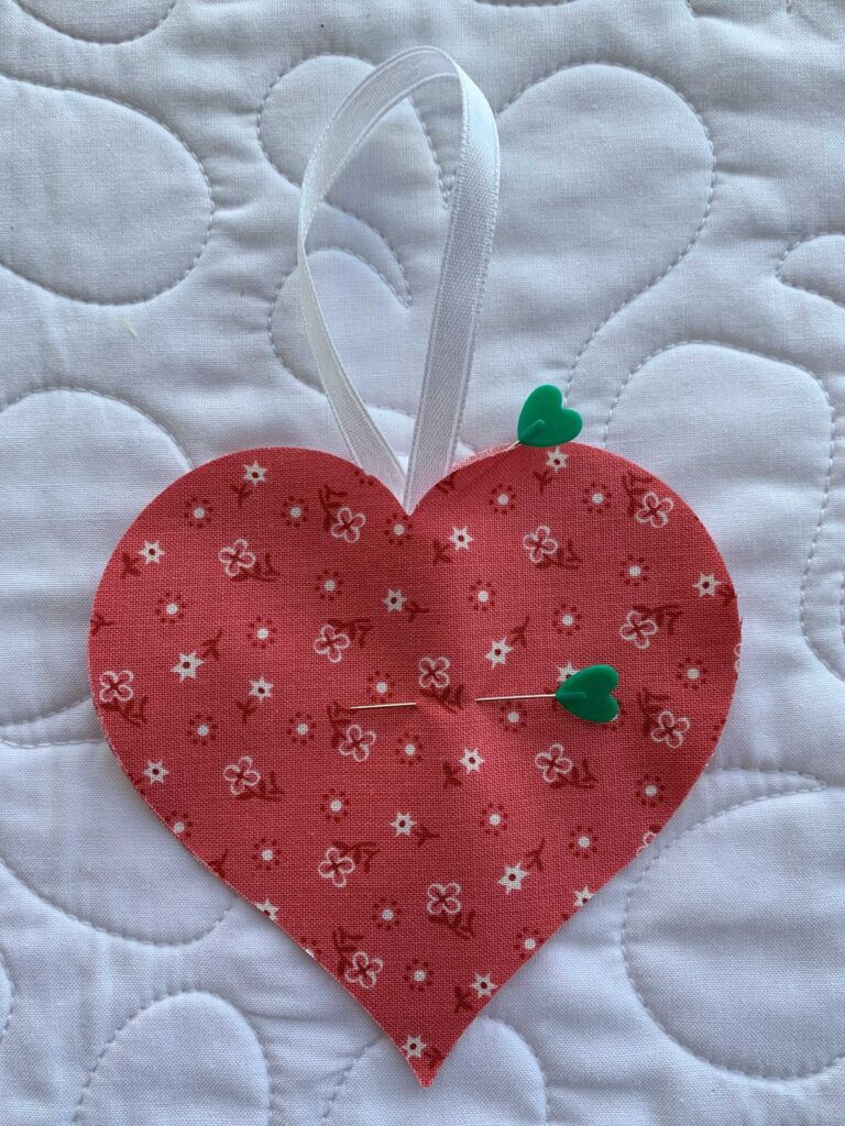 Two hearts with ribbon pinned between. Step 3 in How to Make an Easy Lavender Heart Sachet ~ Tutorial #lavender #lavenderflowers #lavendersachet #lavendersachets #diylavendersachet #lavendersachettutorial #lavendersachetbags #sewlavendersachet #diytutorial #sewingtutorial #diygifts 