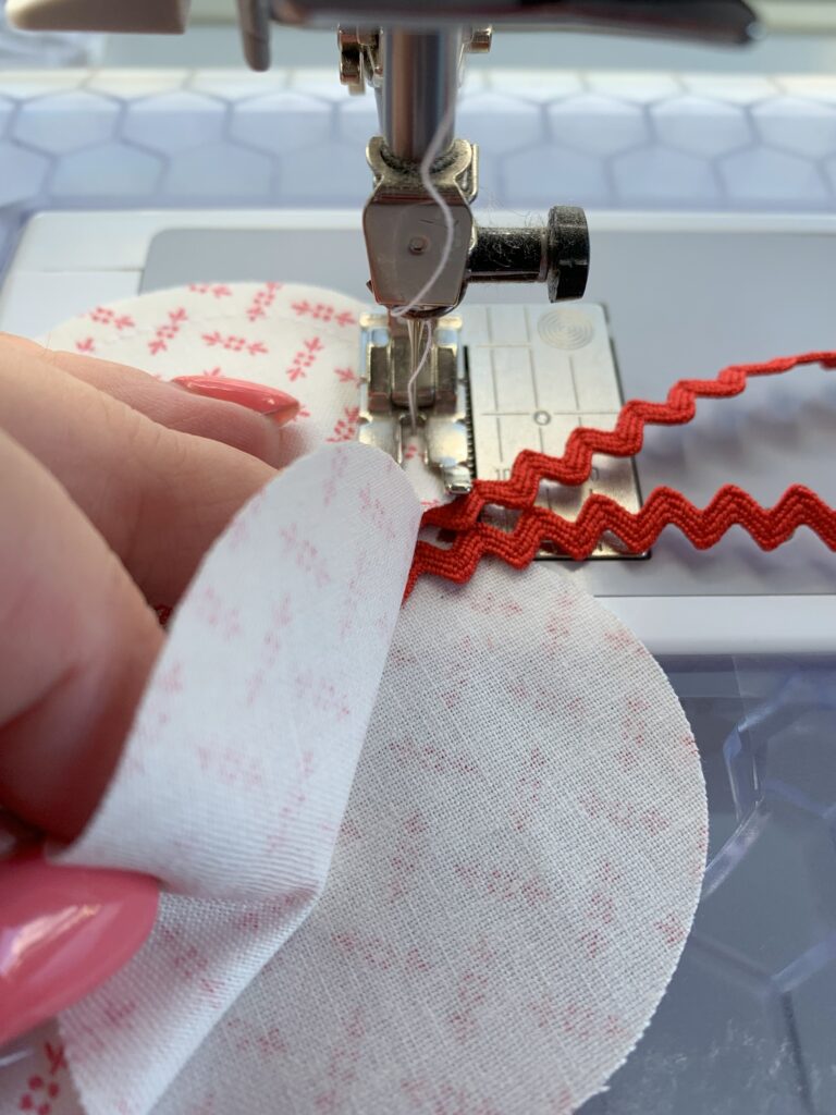 Sewing ricrac in between two hearts to make a heart shaped lavender sachet. Extra option in How to Make an Easy Lavender Heart Sachet ~ Tutorial #lavender #lavenderflowers #lavendersachet #lavendersachets #diylavendersachet #lavendersachettutorial #lavendersachetbags #sewlavendersachet #diytutorial #sewingtutorial #diygifts